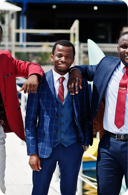 Three FGC Kano alumni in suits with arms around each other