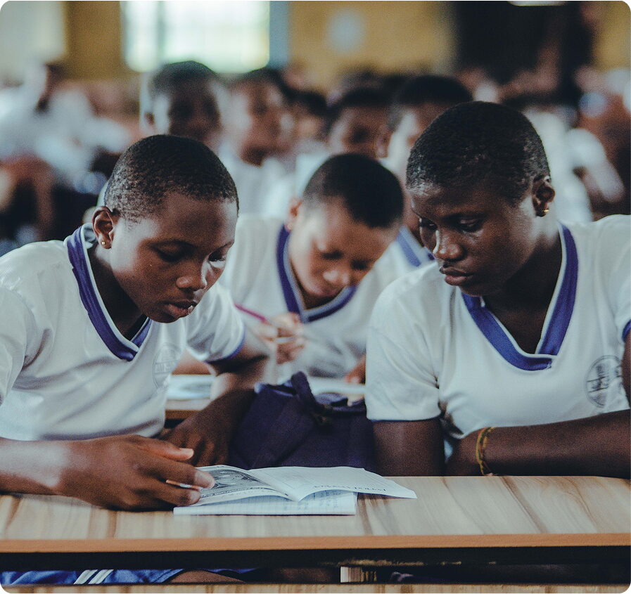 FGC Kano students in white and navy uniforms studying from open textbooks at classroom desks