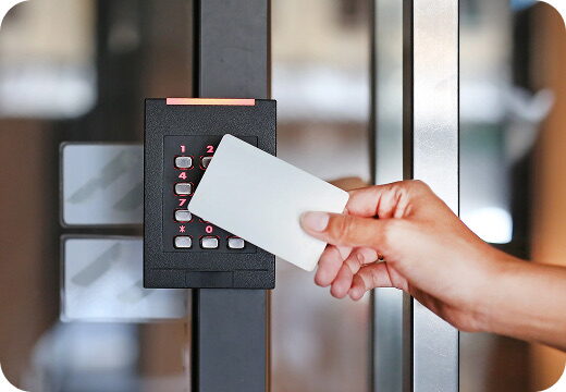 A hand presenting an access card to a door reader